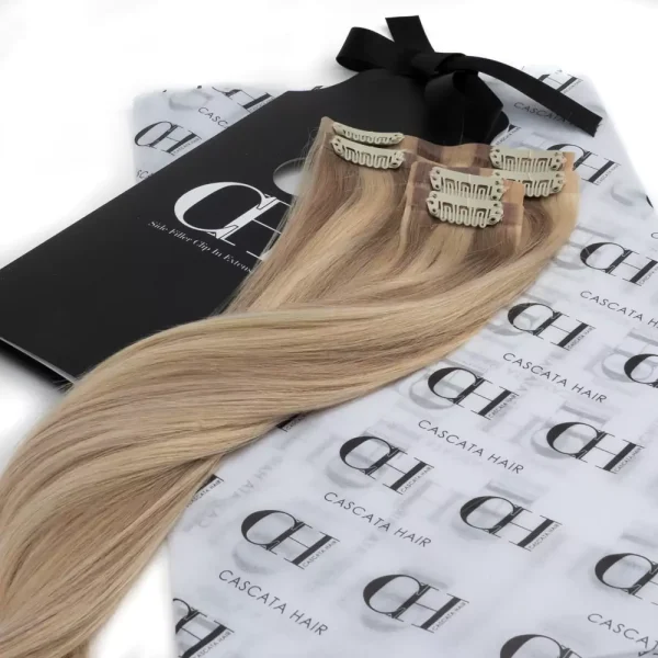 Cascata Hair Extensions - Creamy Blonde Full Set - Image of blonde hair extensions sitting on Cascata branded wrapping paper