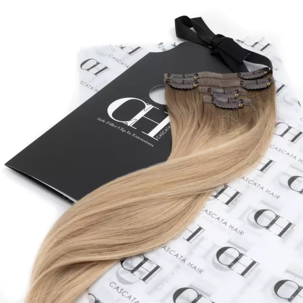 Cascata Hair Extensions - scandanavian blonde Full Set - Image of blonde hair extensions sitting on Cascata Branded Wrapping Paper, which is white, with Black Cascata logos repeated on it.